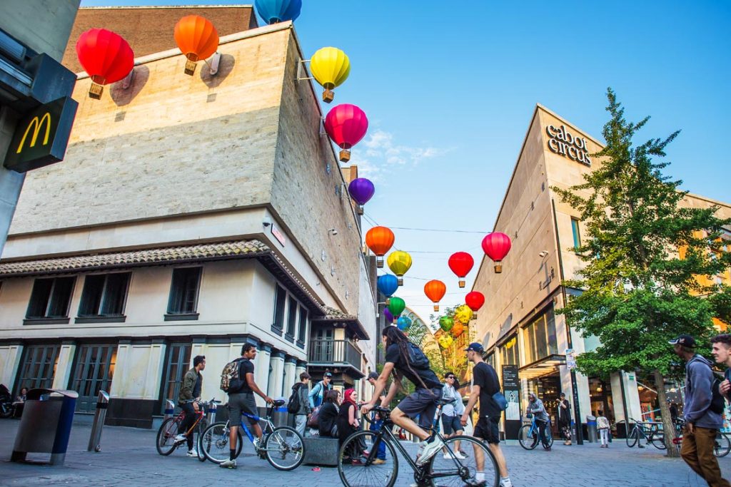 Colourful hanging lanterns above cyclists at Cabot Circus, Bristol