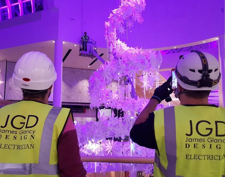James Glancy Design electricians in hard hats installing a lit Christmas sculpture